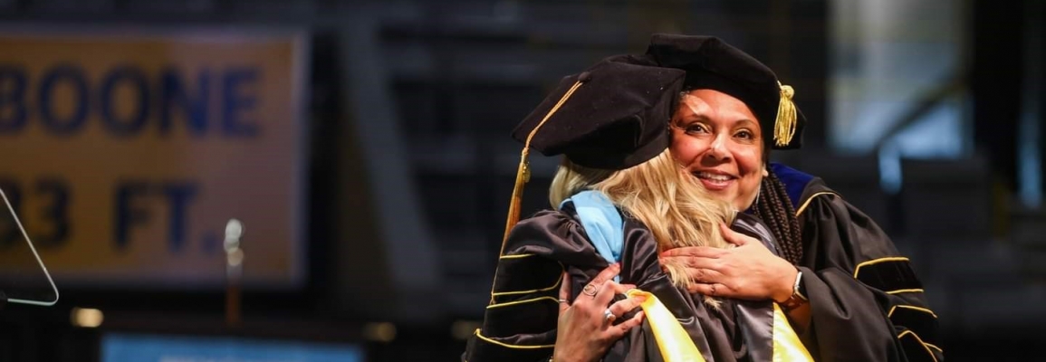 Dr. Shawn Ricks hugging graduate Dr. Jennifer McLean at the Spring 2023 University Commencement Ceremony